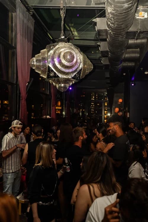 Rooftop venue at Suave Saturdays filled with party-goers, large disco ball hanging from the ceiling, and vibrant lighting.