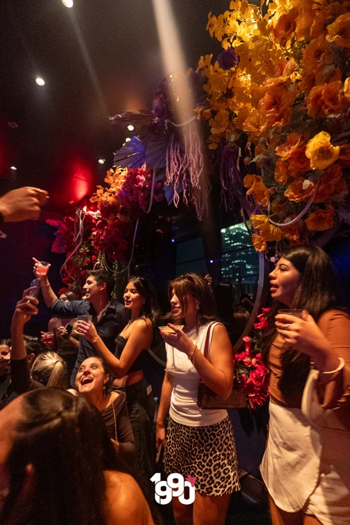 Group of women raising drinks and enjoying the night, surrounded by vibrant floral decorations at Suave Saturdays.