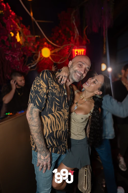 Man and woman posing together and smiling, surrounded by festive decorations at Suave Saturdays in Manhattan.