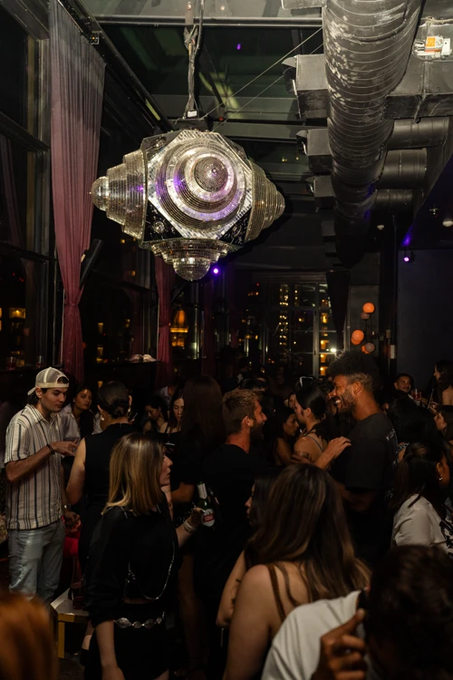 Rooftop venue at Suave Saturdays filled with party-goers, large disco ball hanging from the ceiling, and vibrant lighting.